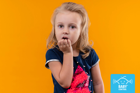 Niña de infantil mordiéndose las uñas con gesto serio, un hábito relacionado con la ansiedad infantil y la onicofagia en niños.