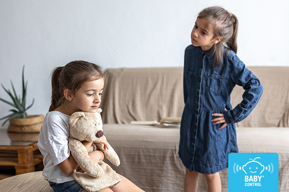 Dos hermanas pequeñas discuten por un peluche durante el verano, una escena habitual de conflictos entre hermanos en la infancia.